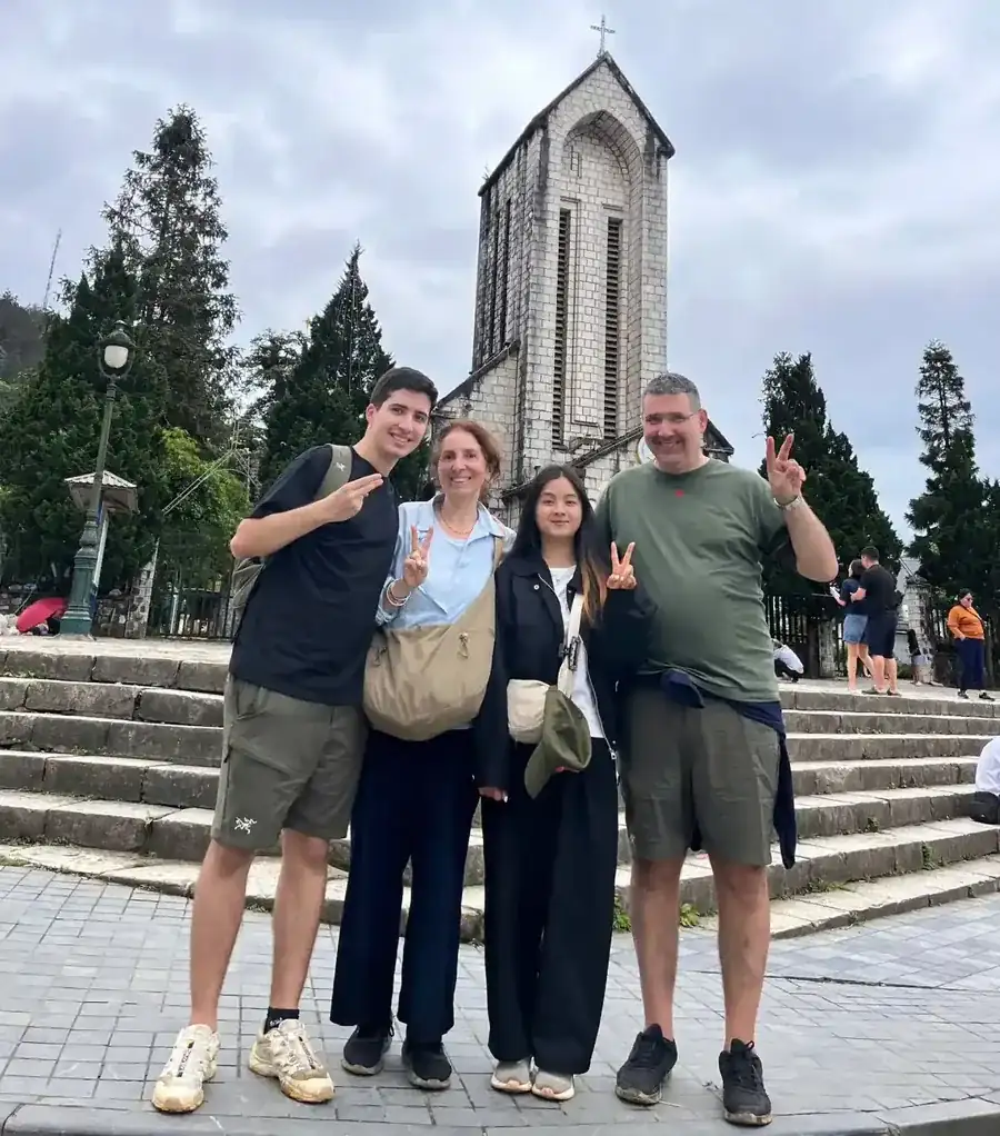Family of travelers posing in front of Sapa Stone Church with their local guide during a Sapa Town walking tour