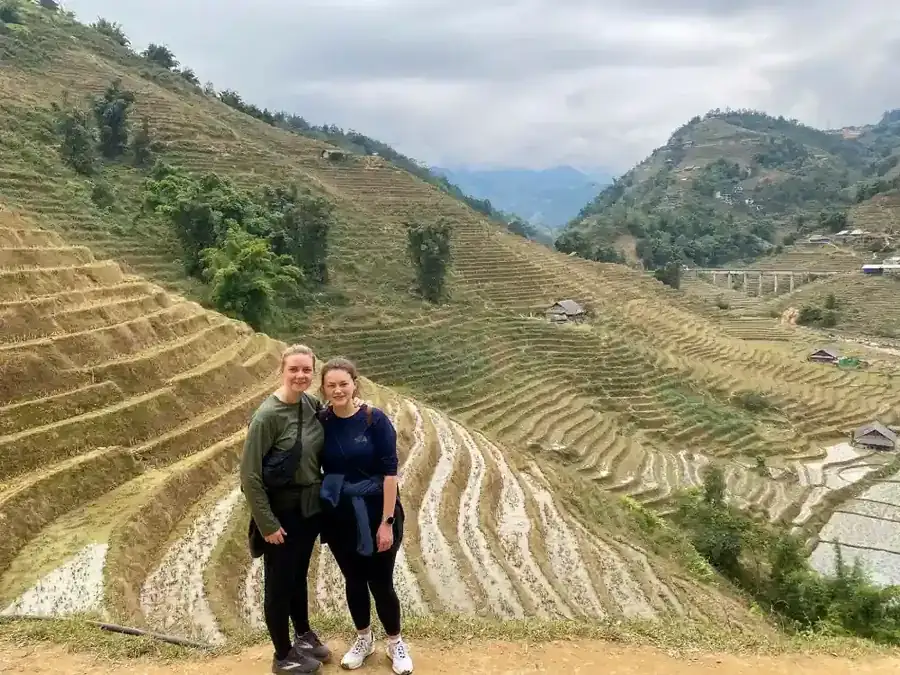 Two travelers smiling in front of Sapa's vast rice terraces during an easy trekking experience